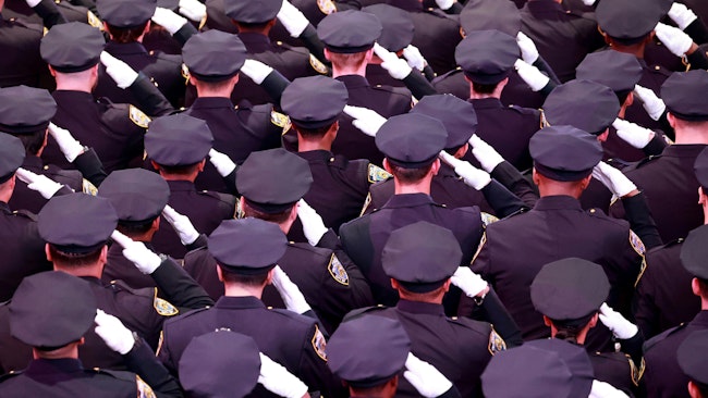 Hundreds of NYPD recruits stand and salute during their 2022 graduation ceremony to full fledge police officers.