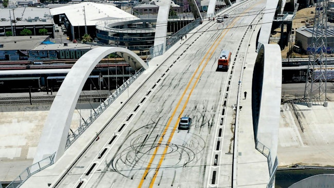 Traffic moves along the new Sixth Street bridge in Los Angeles in 2022, and skid marks can be seen on the pavement after a street takeover.