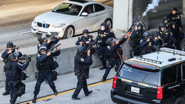 California Highway Patrol officers take aim at protesters throwing rocks at them as they run to their parked cruisers under a freeway overpass June 8 in Los Angeles.