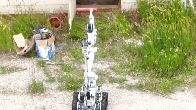 Johnny 5-0, a Douglas County, CO, Sheriff's Office bomb squad robot, grabs an old dynamite stick from a shed to help dispose of it with a controlled detonation