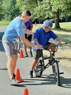 Calvert County SRO DFC Shane Naughton teaches a camper how to ride a bicycle. Calvert County SRO DFC Shane Naughton teaches a camper how to ride a bicycle.