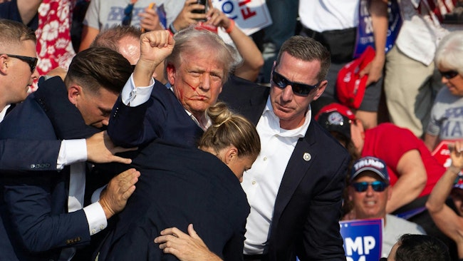 Then-presidential candidate Donald Trump is seen with blood on his face surrounded by Secret Service agents as he is taken off the stage at a rally in Butler, PA, on July 13, 2024.