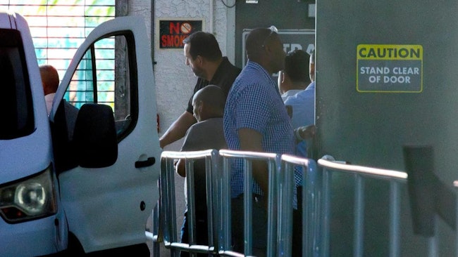 U.S. Immigration and Customs Enforcement (ICE) agents escort a group of men into a van following their arrest outside the Executive Office for Immigration Review in Miami in May.