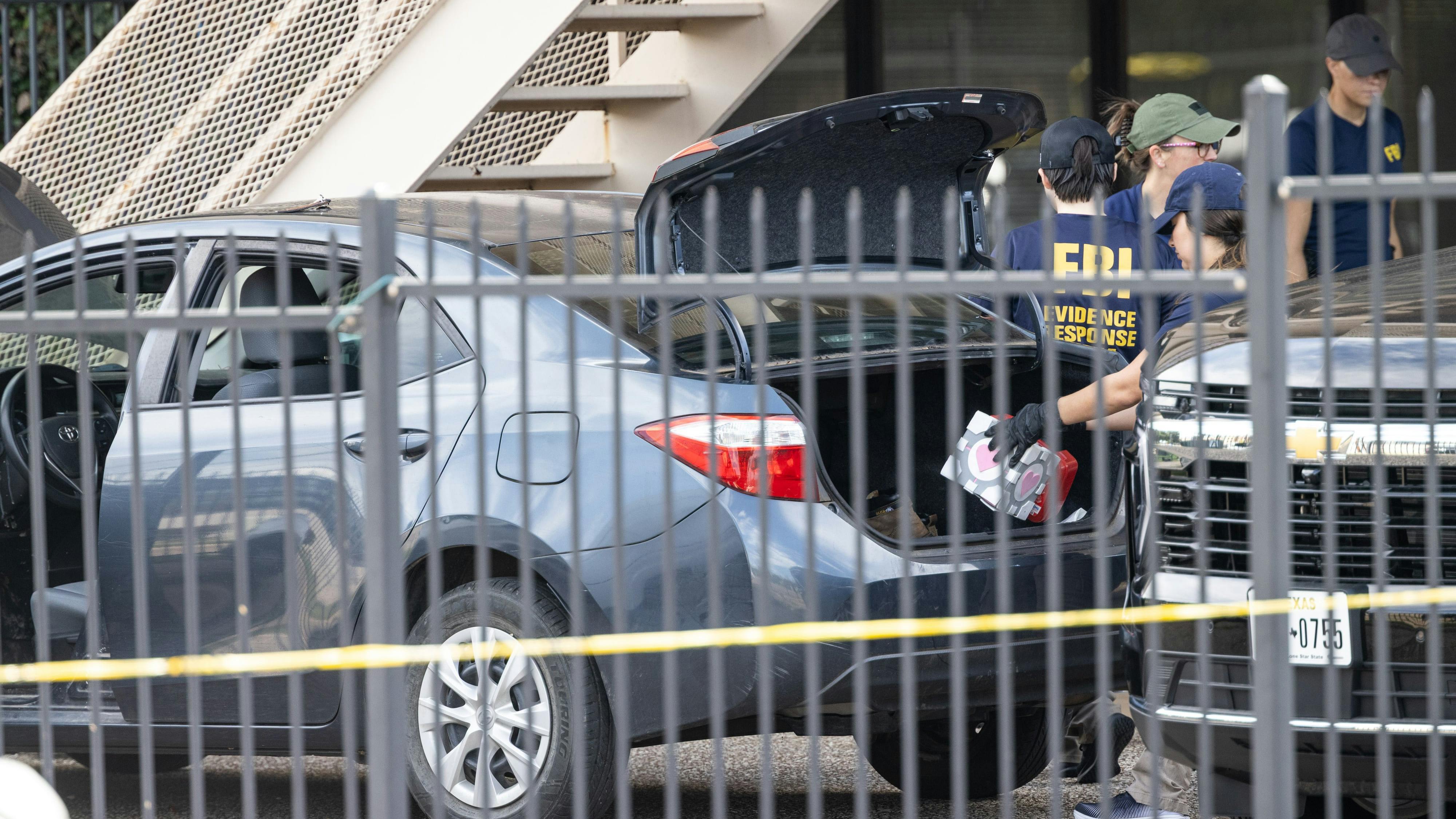 FBI officials investigate Wednesday a vehicle outside of an immigration attorney's office behind the Dallas field office for U.S. Immigration and Customs Enforcement office after a shooting that killed one detainee and critically wounded two others..