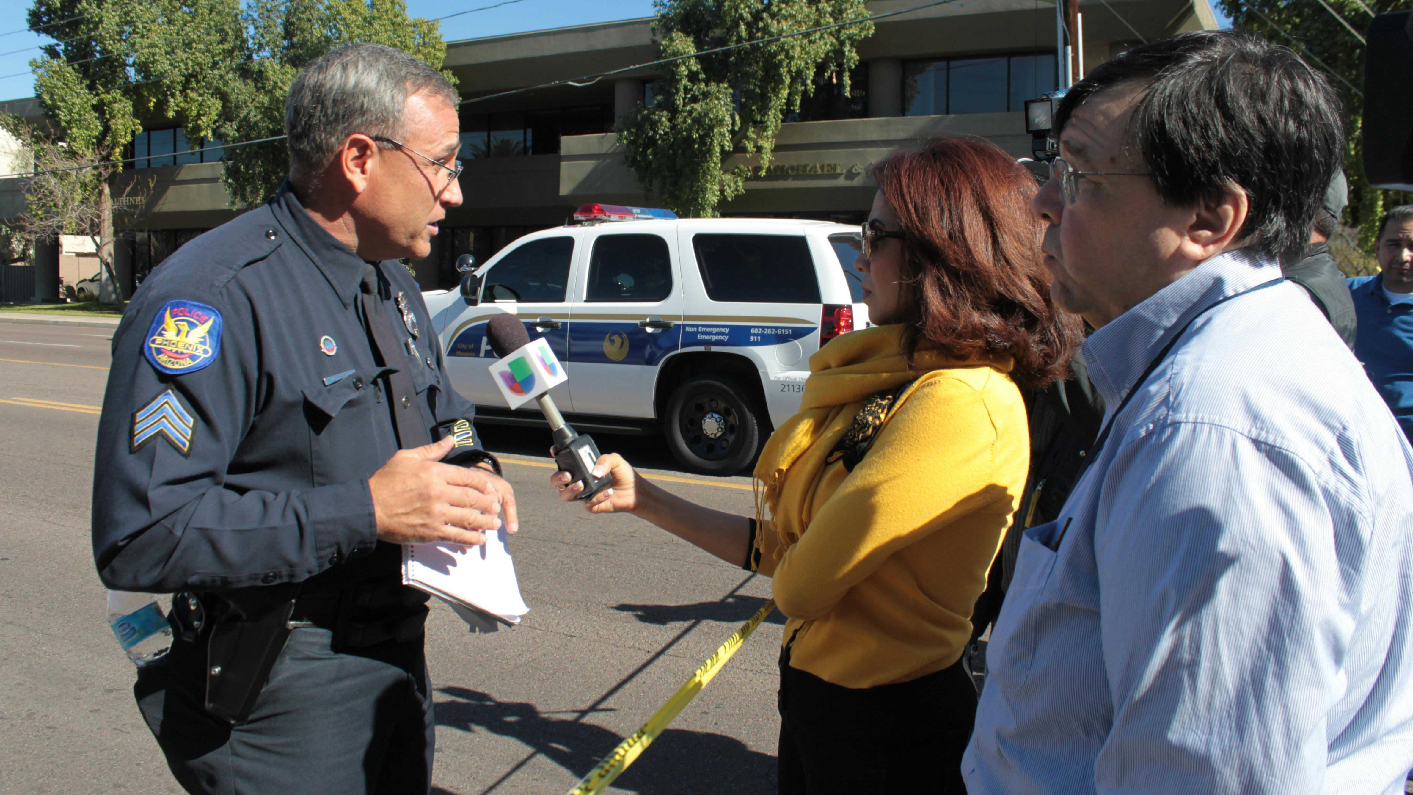 A Phoenix police officer briefs journalists after a 2013 workplace shooting leaves two people dead, one injured and a suspect at large.