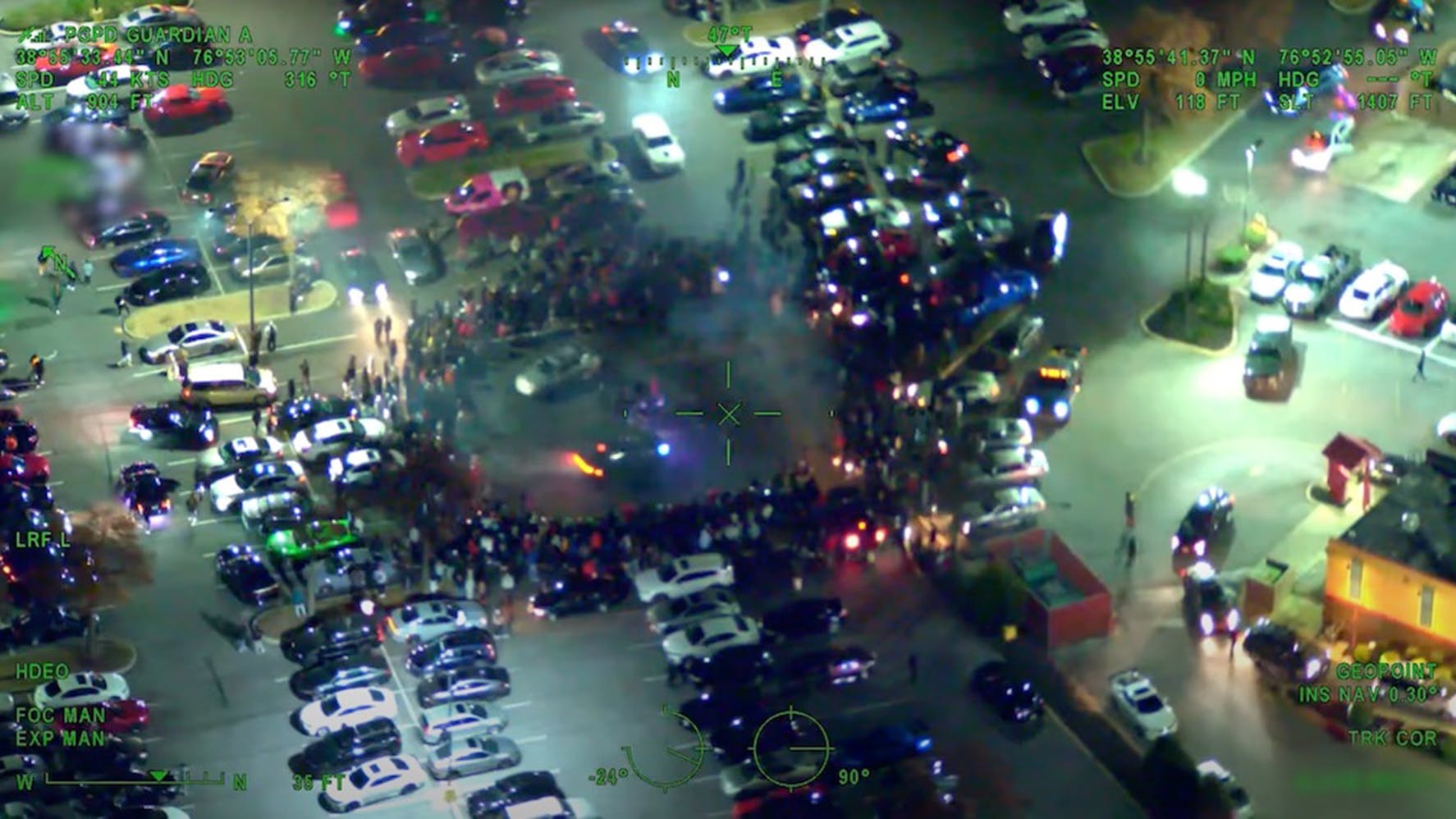 Two cars drive in a circle amid a crowd of onlookers during an illegal street takeover in Prince George&rsquo;s County, MD. These events, in which drivers block roads to perform stunts, have become an increasing concern for pol in cities across the country.