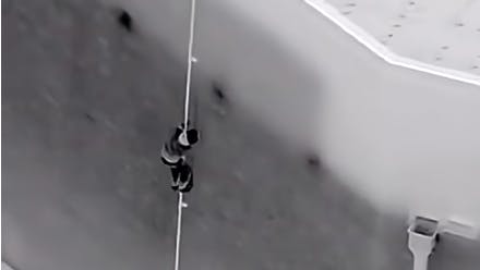 A suspect in an attempted burglary climbs down from the roof of a Modesto, CA, Best Buy store Monday.