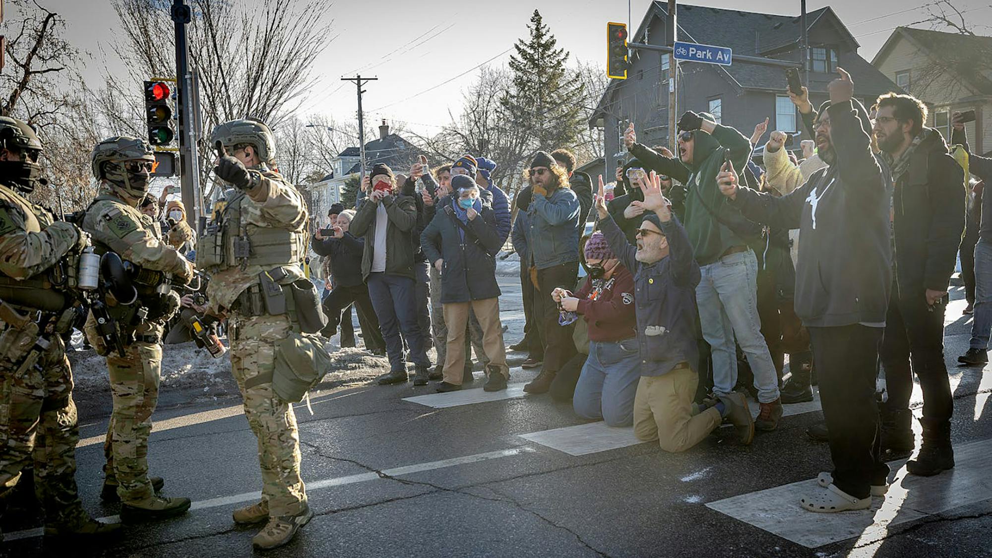Protesters, some filming with their phones, yell at federal agents on Jan. 13, 2026, near where Renee Good was killed in Minneapolis.