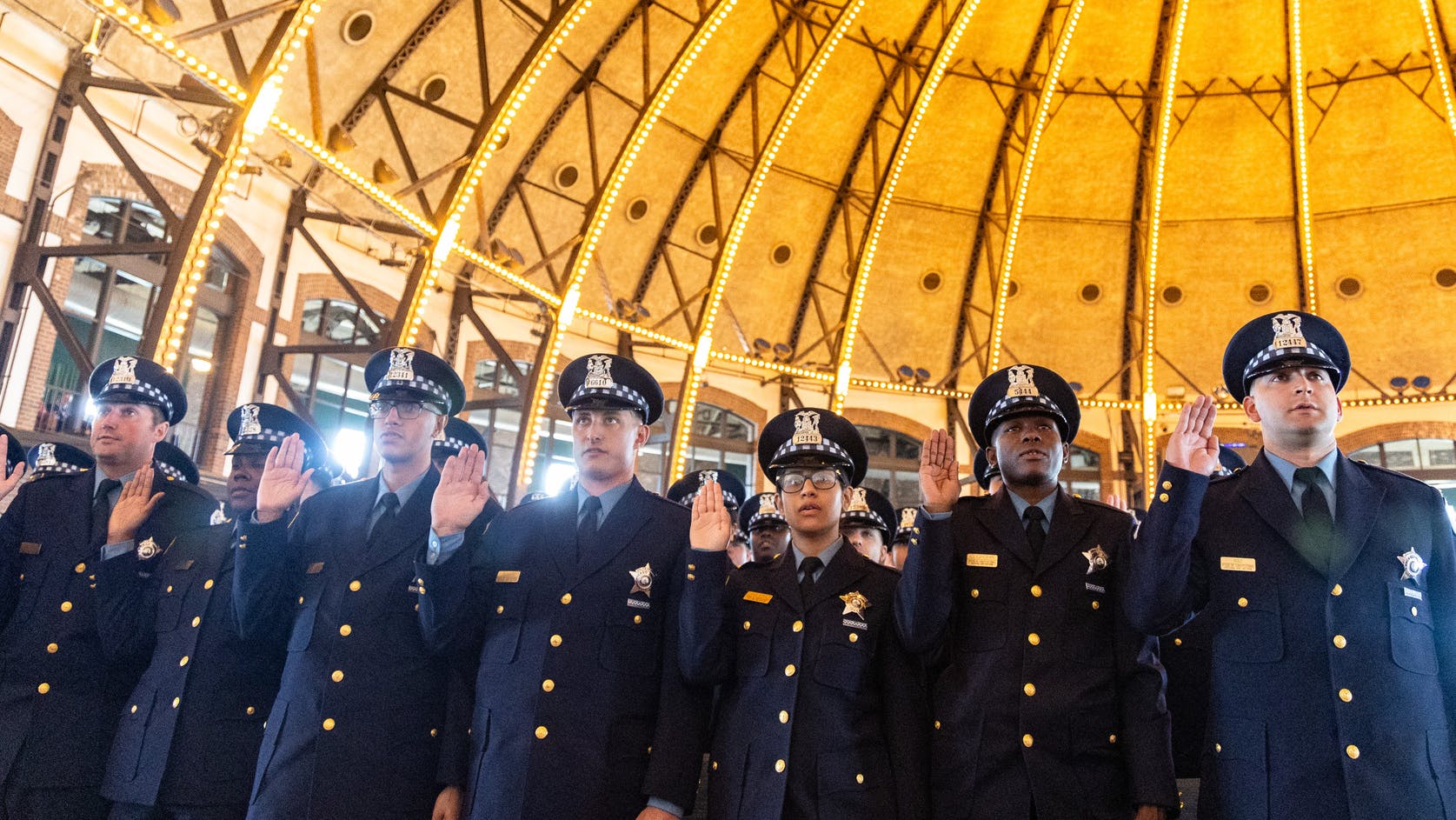 Chicago police recruits take the oath of office during a department graduation and promotion ceremony in 2025. A workforce study recommends hiring an additional 270 officers and shifting about 600 positions to civilians.