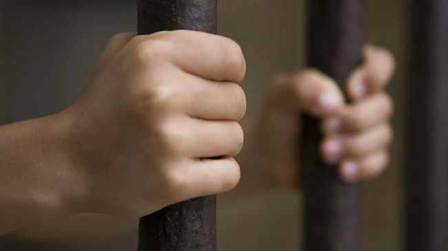 Hands on prison bars