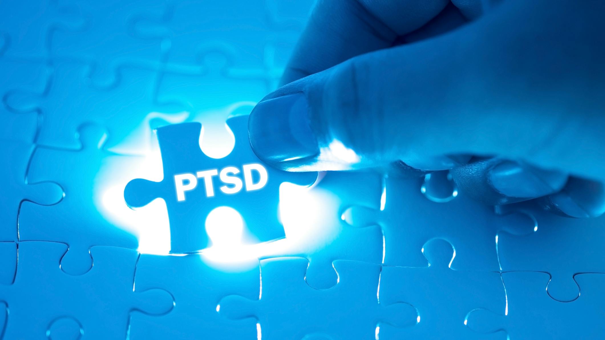 Hand holding a blue PTSD puzzle piece