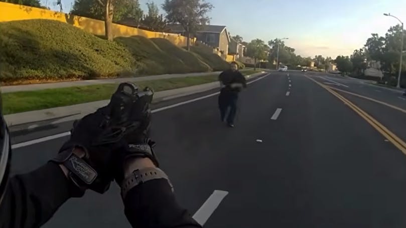 A Corona police officer with his gun drawn backs away as a suspect accused of attacking an elderly woman with a rock advances with a knife