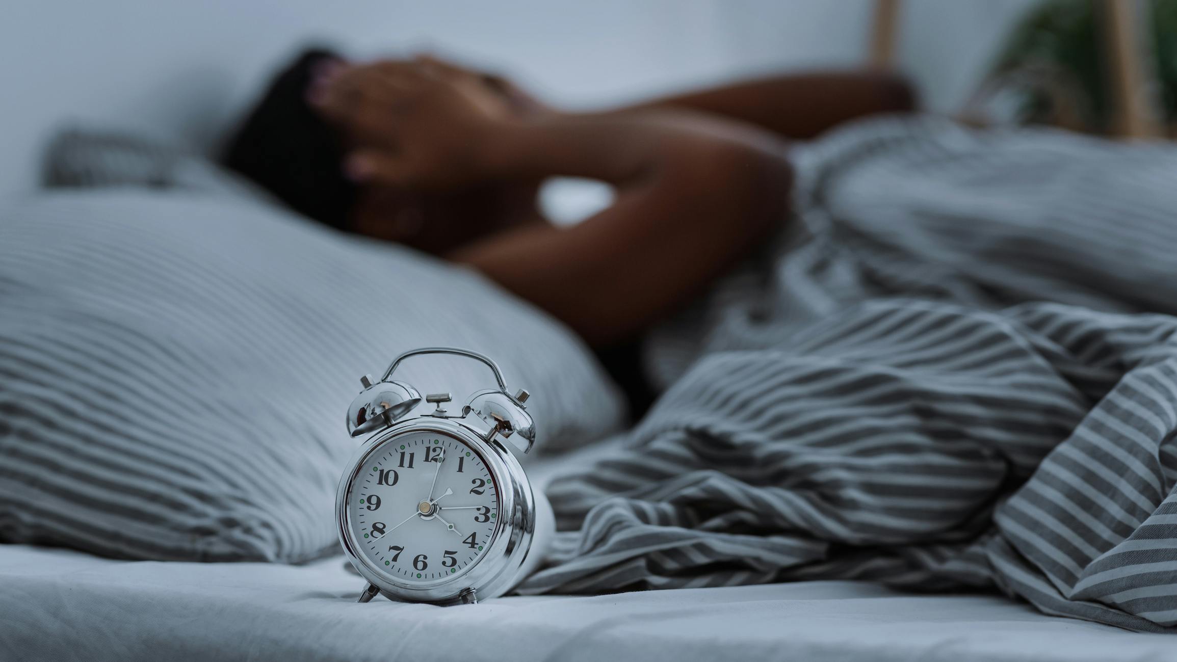 Waking up in bed with an alarm clock in the foreground