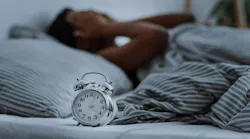 Waking up in bed with an alarm clock in the foreground