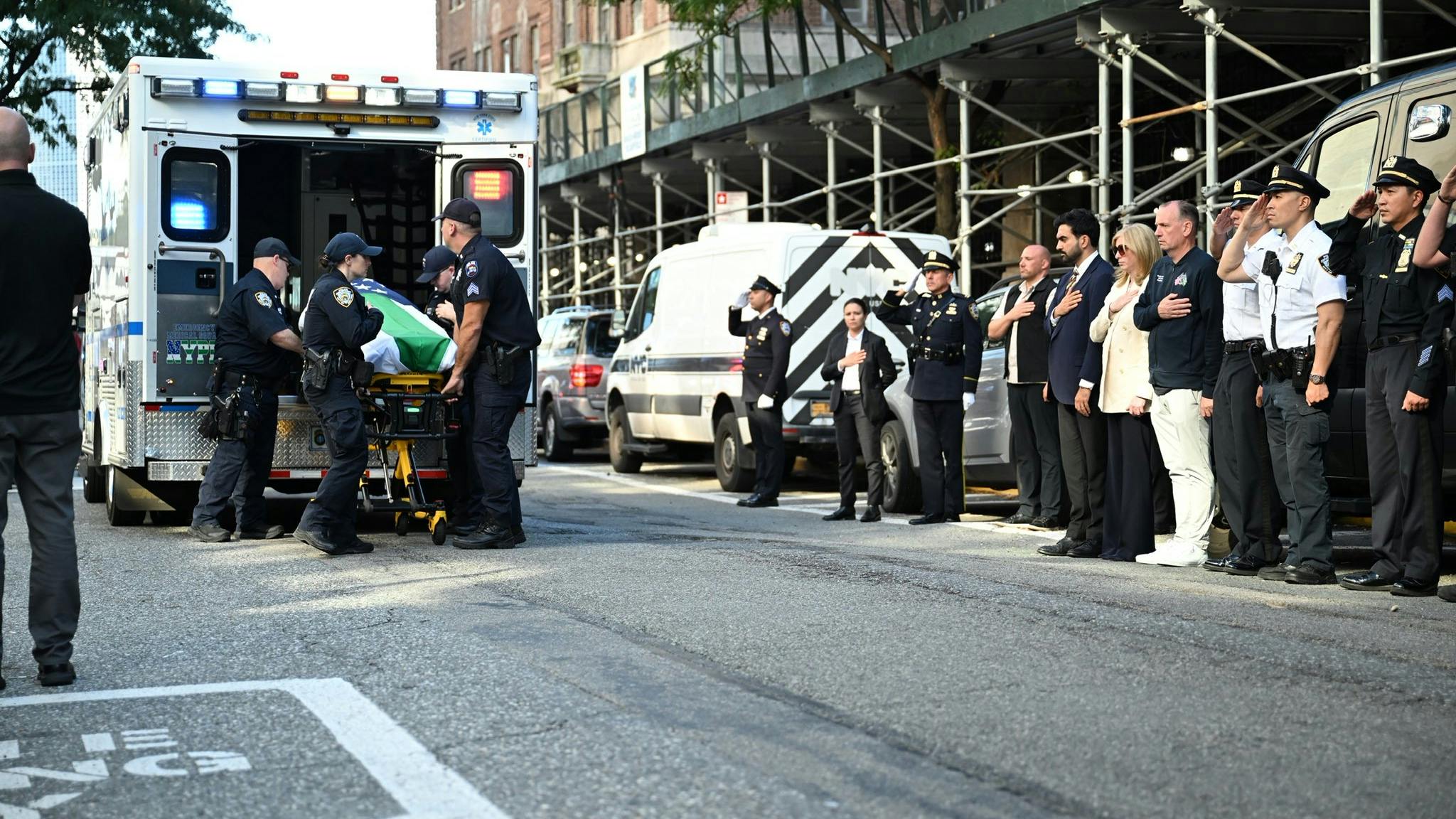 The body of Kamir Loubarria, a probationary NYPD recruit, is put into an ambulance as officers and medical personnel look on