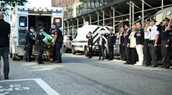 The body of Kamir Loubarria, a probationary NYPD recruit, is put into an ambulance as officers and medical personnel look on