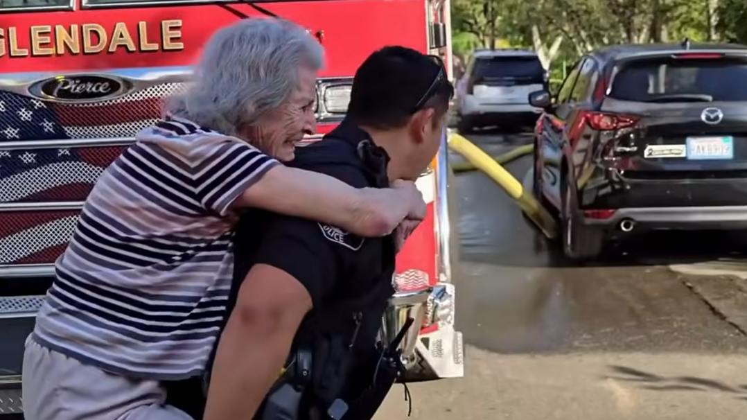 A Glendale police officer carries a resident to safety during a nursing home fire
