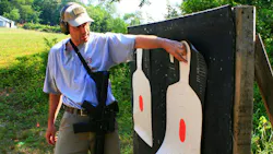 A firearms instructor points at a target during a training session