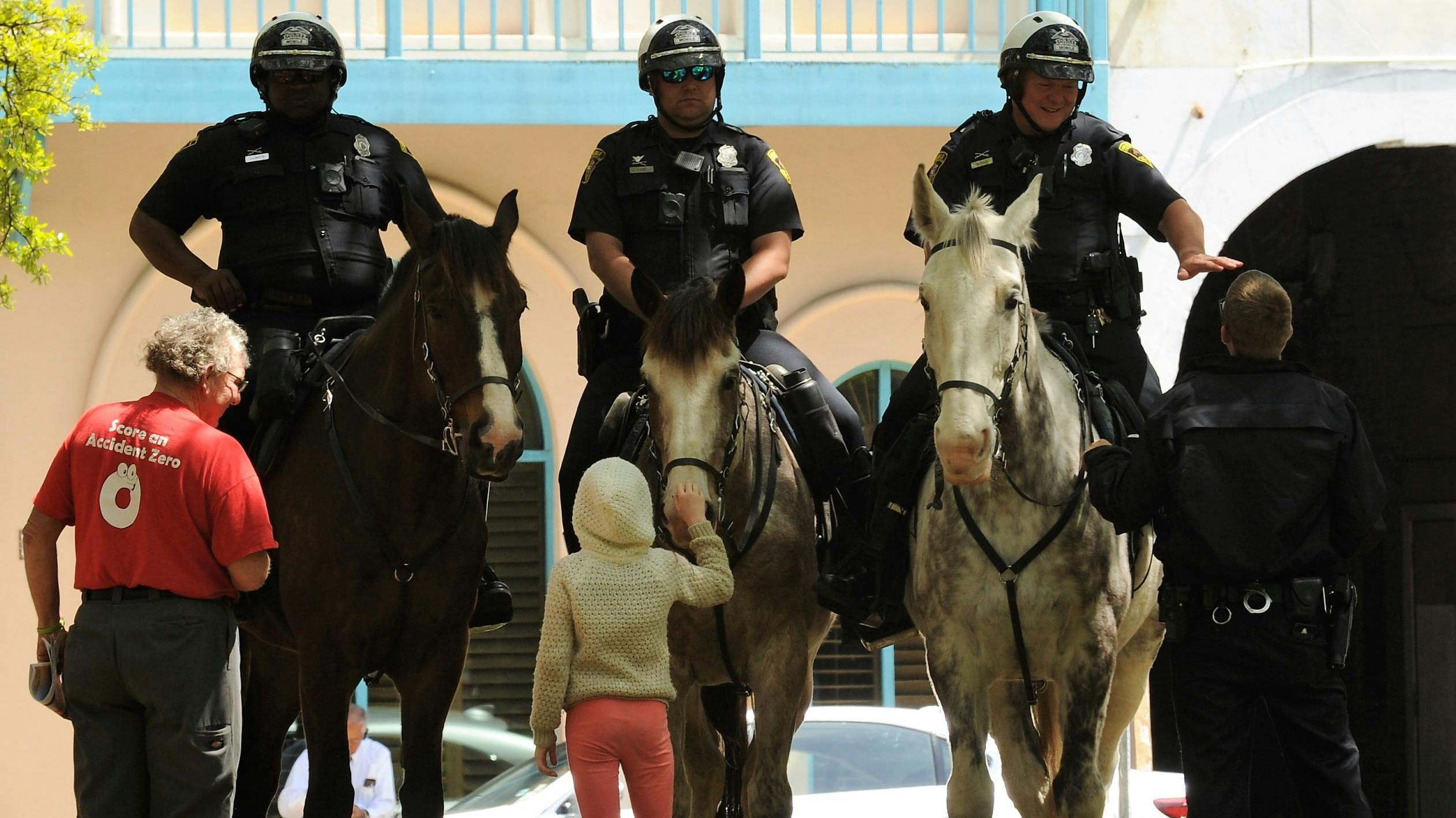 A girl pets a Mobile police mounted unit horse during a concert in Bienville