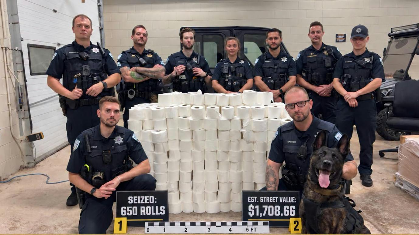 Plainfield police pose in front of 650 rolls of toilet paper seized in a crackdown of homecoming-related vandalism