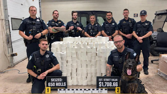 Plainfield police pose in front of 650 rolls of toilet paper seized in a crackdown of homecoming-related vandalism