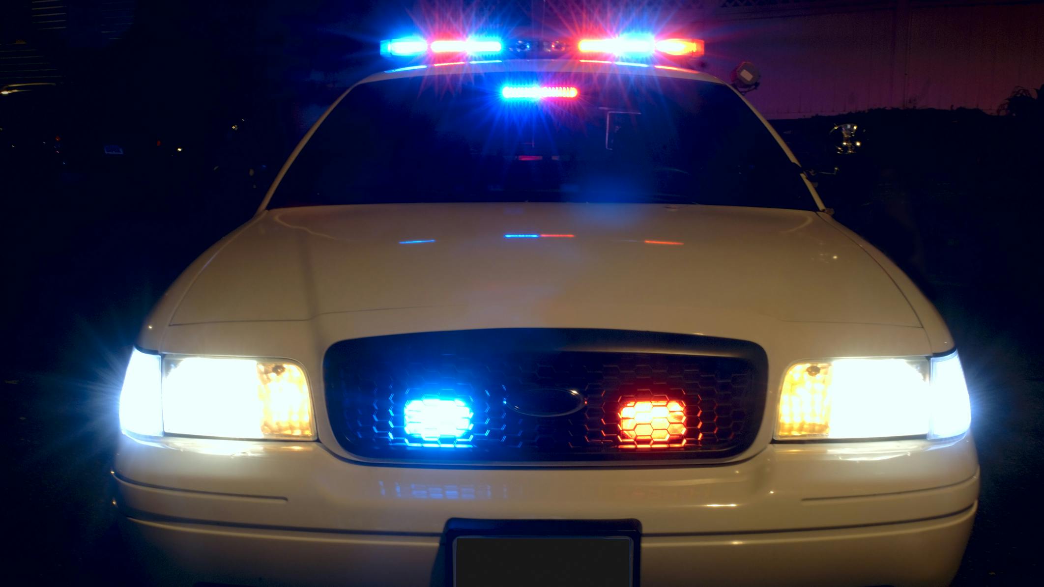 The front of a police cruiser with its emergency lights activated