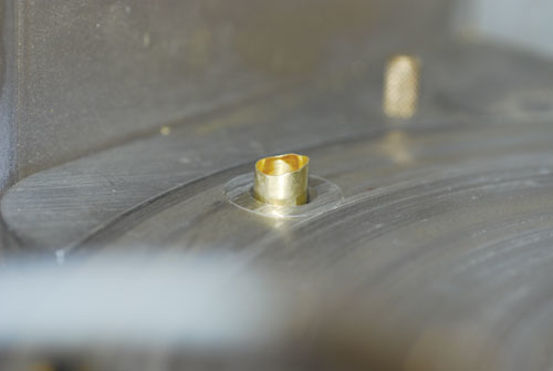 The cold-forming process causes shell casings to have an uneven mouth. This view shows the casing mouth protruding upward throug