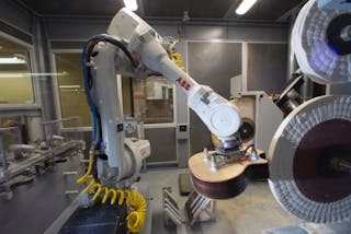 An ABB IRB 4600 robot positions a guitar body against the buffing wheel.