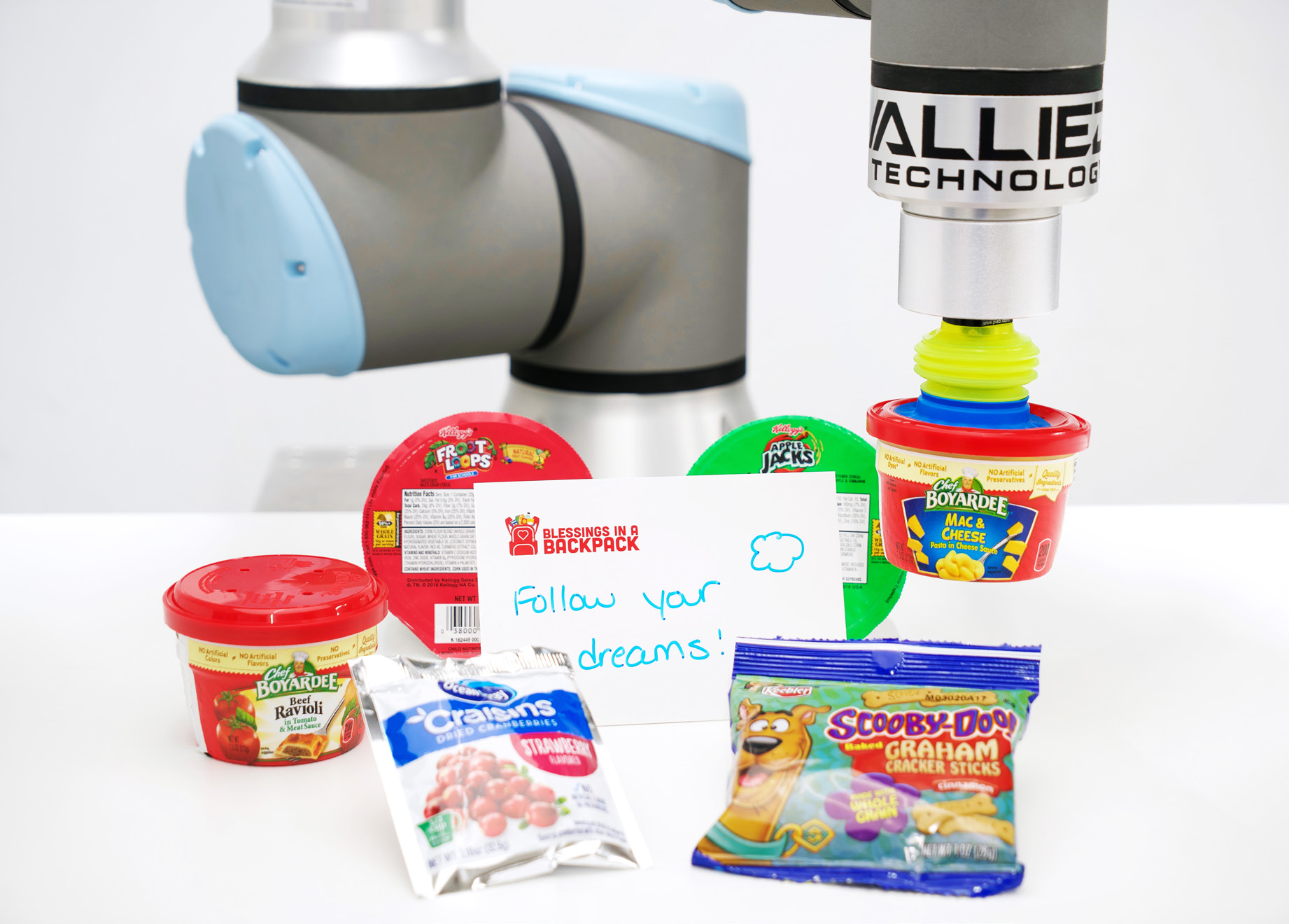 A four-cobot line picks random product and loads food into a pouch destined for Blessings in a Backpack.