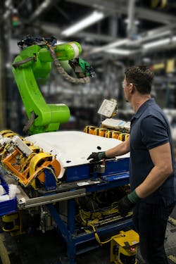 A CR-35iA collaborative robot from Fanuc working in tandem with a technician on an automotive headliner gluing application.