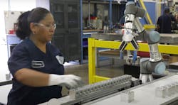 Tomeson employee moves stamped blocks from cobot workcell. Tomeson employee moves stamped blocks from cobot workcell.