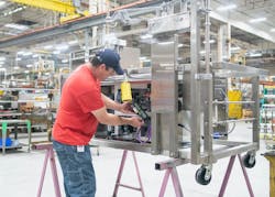 John Priddy, Krispy Kreme fabrication manager, installs the G120 kit into the fryer section of a doughnut machine. Source: Siemens