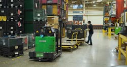 A worker engages with a stopped Vecna Robotics ATG Autonomous Tugger to load goods as it passes by his work station. Source: Vecna Robotics
