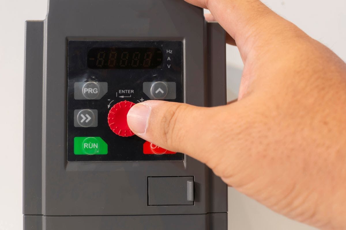 Close-up of a hand adjusting settings on an inverter variable speed drive