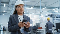 Manufacturing engineer using apps on smartphone Manufacturing engineer using apps on smartphone